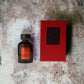 Acqua di Parisis Essenza Intensa Oud Couture Parfumflakon mit roter Verpackung auf Marmoruntergrund