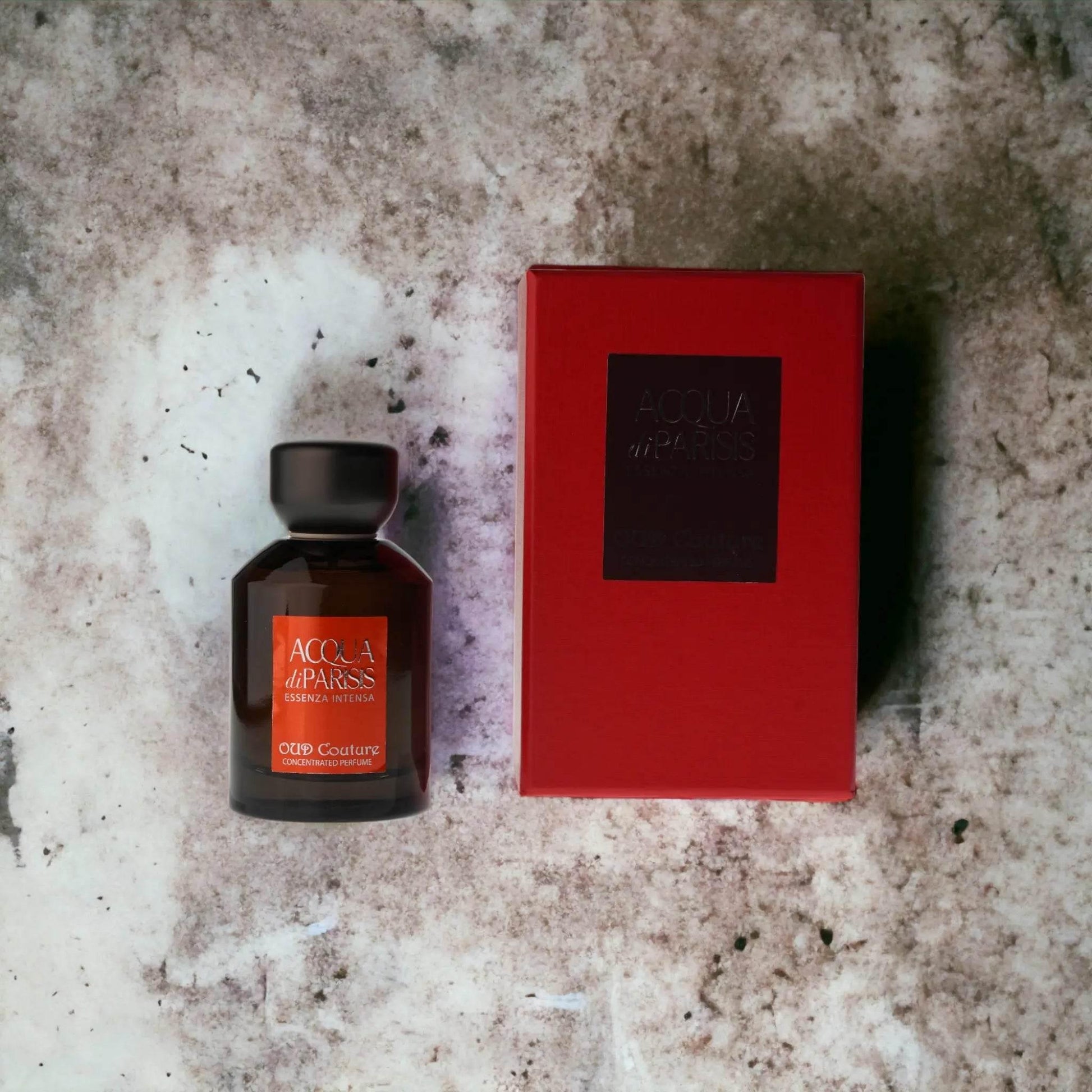 Acqua di Parisis Essenza Intensa Oud Couture Parfumflakon mit roter Verpackung auf Marmoruntergrund