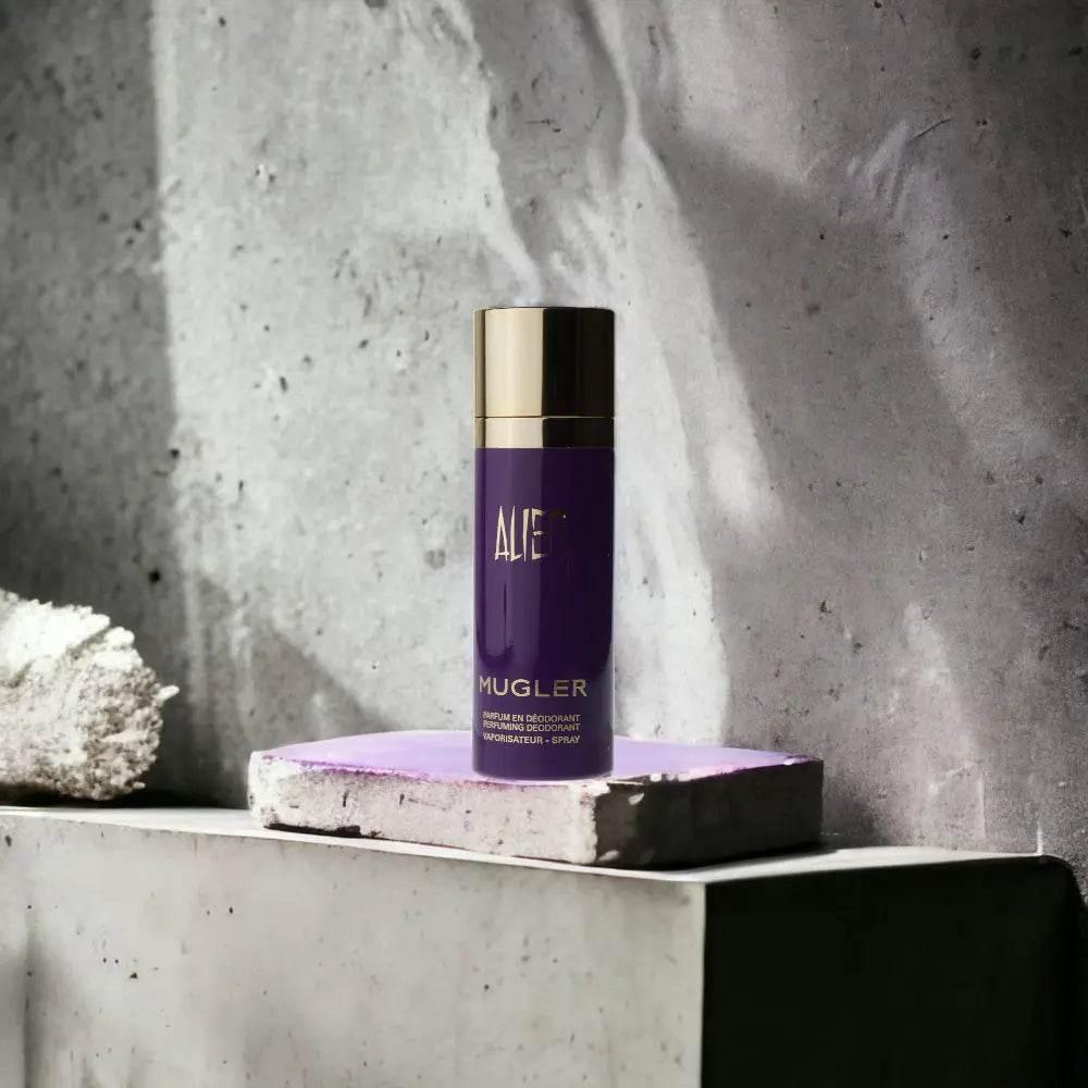 Lila Mugler Alien Deodorant Spray mit goldener Kappe auf grauem Stein, luxuriöses Design