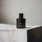 Schwarzer Flakon Gisada Ambassador Intense Eau de Parfum auf grauem Stein, luxuriöser Herrenduft