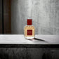 Gisada Ambassadora Eau de Parfum Flakon mit rotem Etikett auf Betonoberfläche
