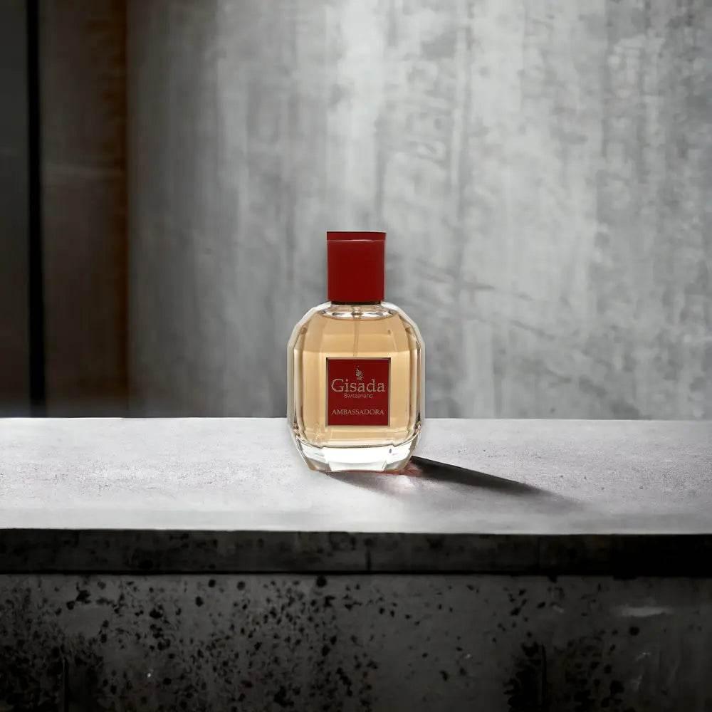 Gisada Ambassadora Eau de Parfum Flakon mit rotem Etikett auf Betonoberfläche
