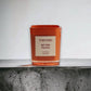 Orange Duftkerze Tom Ford Bitter Peach auf Betonoberfläche, edles Design, Luxuskerze
