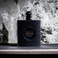 Schwarzer, glitzernder Parfümflakon Black Opium vor marmorierter Wand, Produktfotografie.