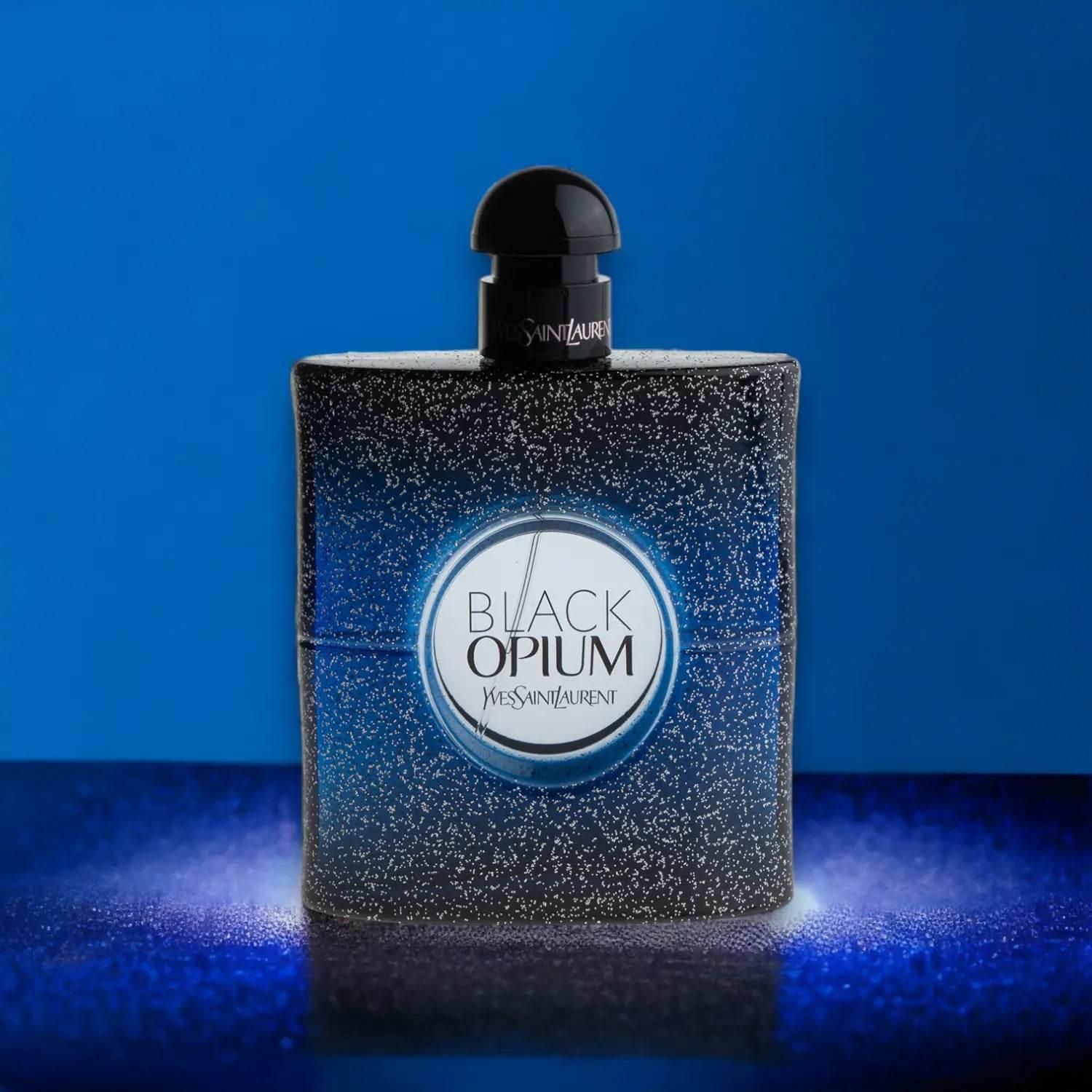 Schwarzer Parfumflakon Black Opium Intense vor blauem Hintergrund, glitzerndes Design.
