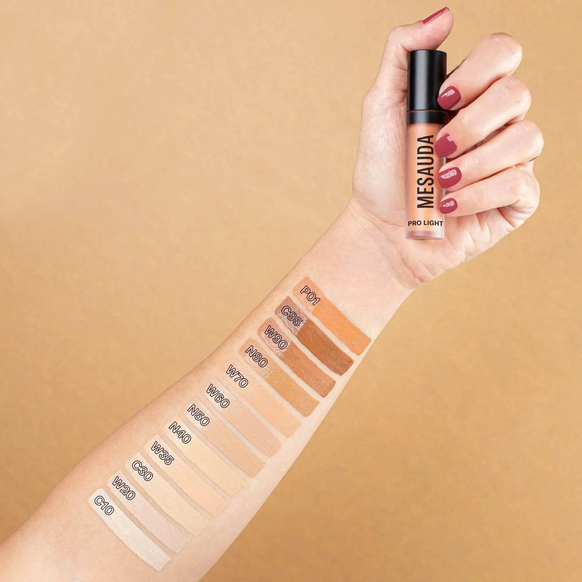 Arm mit Concealer-Farbmustern verschiedener Töne, Hand hält Mesauda Pro Light Concealer