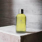 Molton Brown Cardamom & Cedarwood Duschgel Flasche auf Betonuntergrund, Luxuspflege