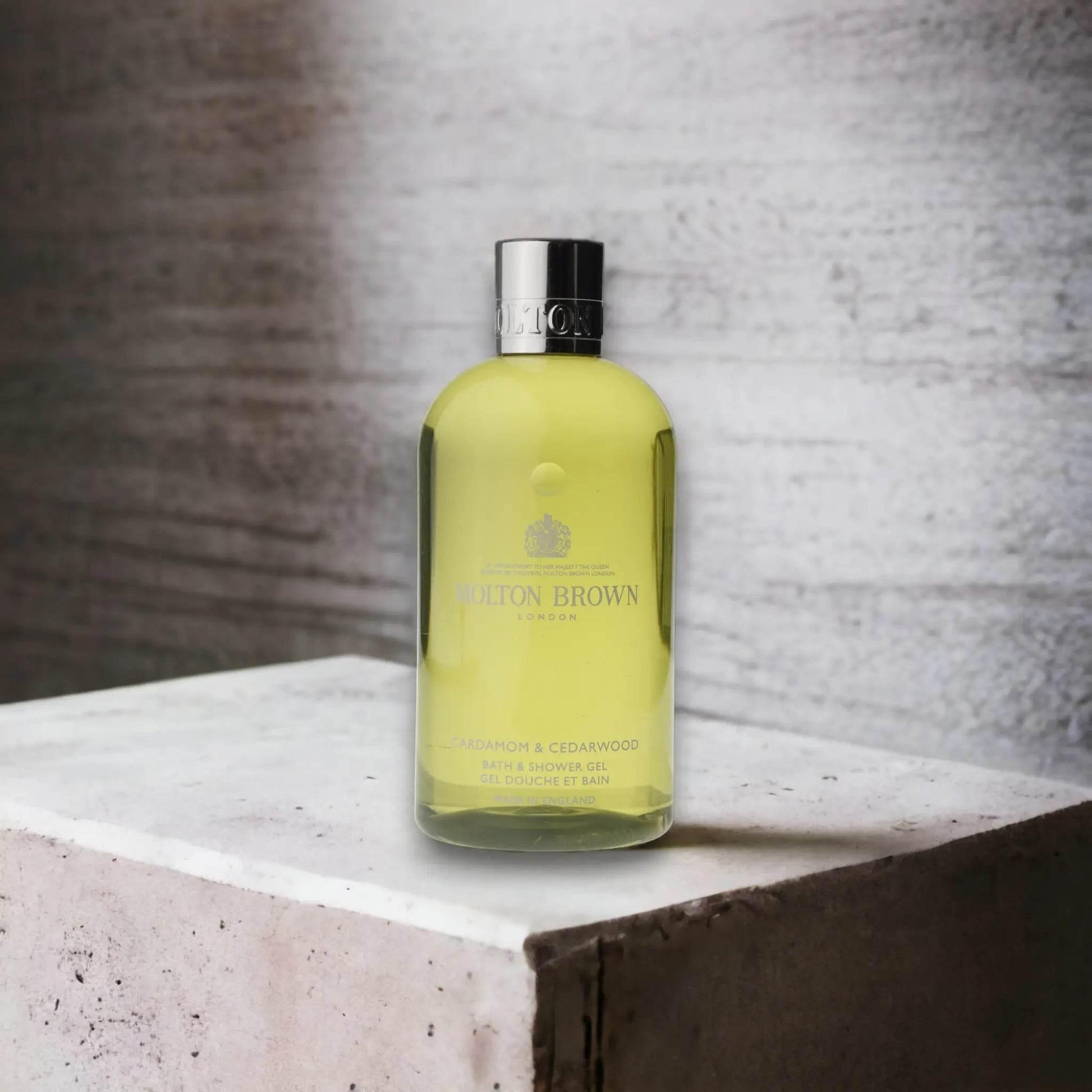 Molton Brown Cardamom & Cedarwood Duschgel Flasche auf Betonuntergrund, Luxuspflege