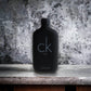 Schwarzer Flakon CK Be Eau de Toilette auf grauem Steinuntergrund, minimalistisches Design
