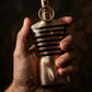 Nahaufnahme einer Hand hält eine goldene, maskuline Parfumflasche mit Streifen-Design