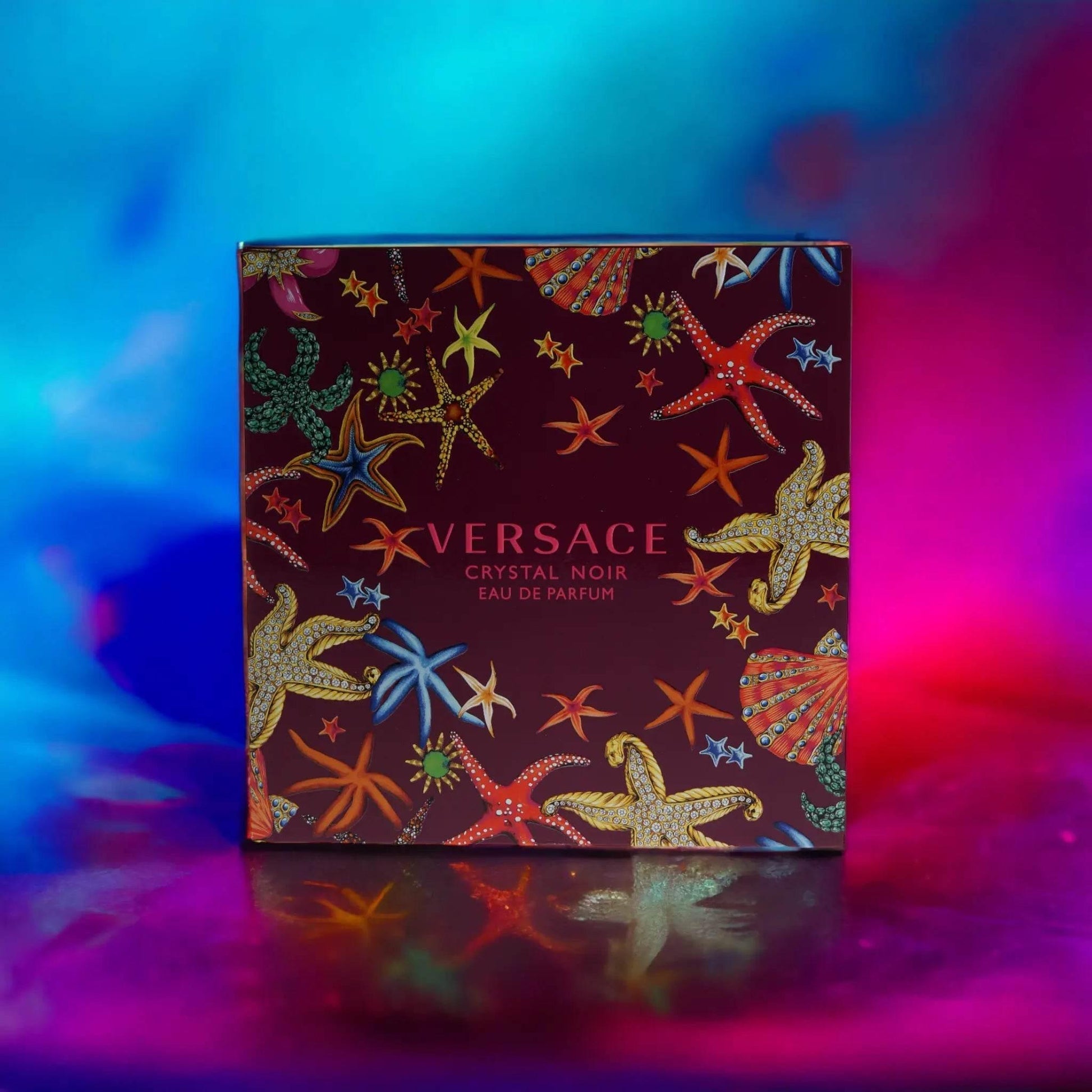 Versace Crystal Noir Eau de Parfum Geschenkset mit buntem Seestern-Design vor buntem Hintergrund