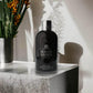 Elegantes schwarzes Duschgel-Flakon Molton Brown Dark Leather auf Marmor, Premium-Kosmetik