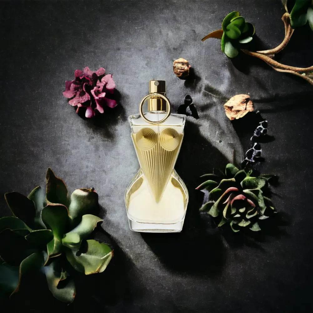 Edles Eau de Parfum in figurförmigem Flakon, umgeben von Sukkulenten und Blüten auf dunklem Hintergrund.