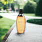 Parfümflakon mit orangefarbener Flüssigkeit auf Holztisch im Freien, Biotherm Eau d’Energie