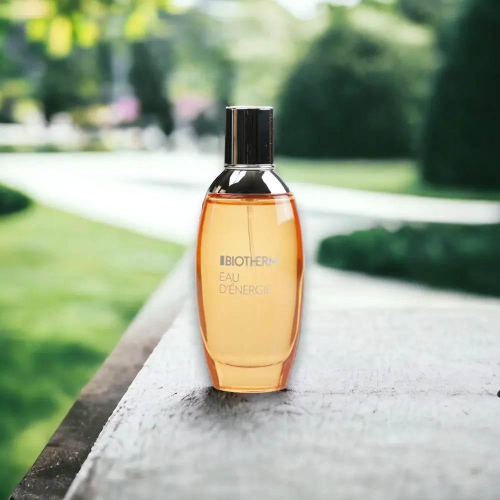 Parfümflakon mit orangefarbener Flüssigkeit auf Holztisch im Freien, Biotherm Eau d’Energie