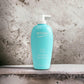 Türkise Flasche Biotherm Eau Pure Body Milk mit Pumpspender vor Steinwand, 400 ml