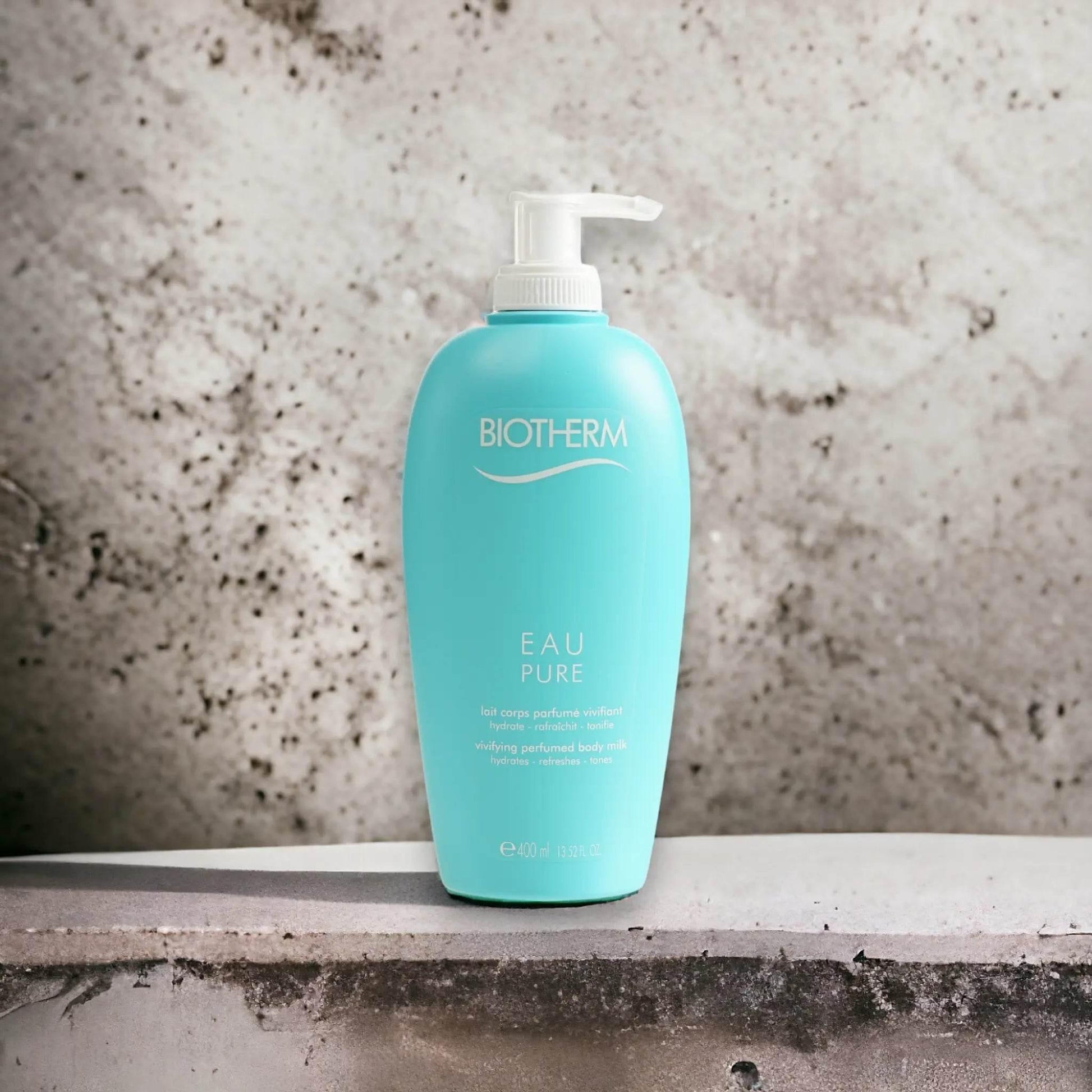 Türkise Flasche Biotherm Eau Pure Body Milk mit Pumpspender vor Steinwand, 400 ml