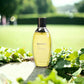 Gelbe Biotherm Eau Vitaminée Parfumflasche, draußen mit grünen Blättern, sonnig