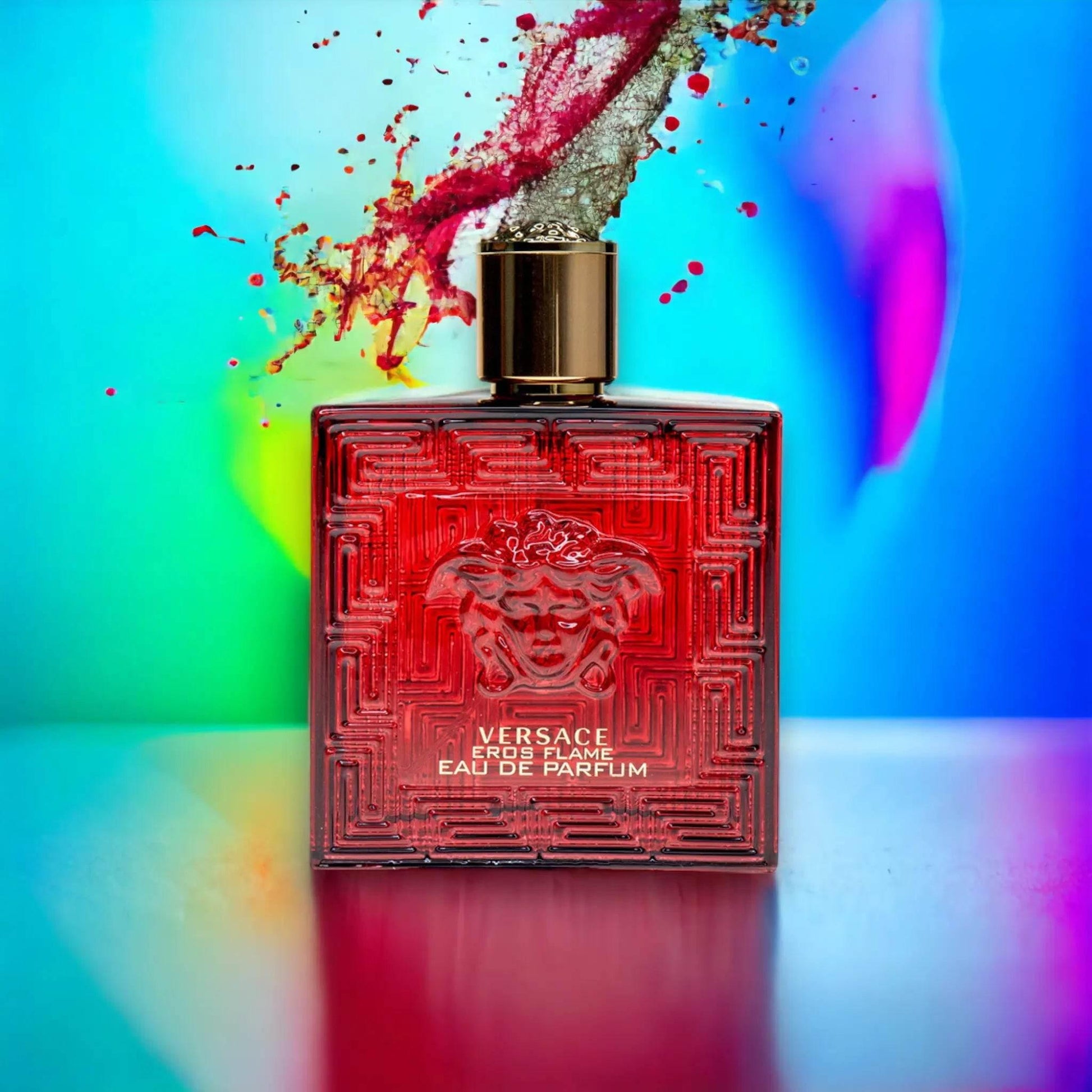 Roter Parfumflakon Versace Eros Flame mit goldener Kappe vor buntem Hintergrund, Duftwolke sprüht heraus.