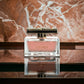 Luxuriöses Eau de Parfum in elegantem Flakon mit roséfarbener Flüssigkeit auf Marmorfläche