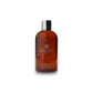Braune Molton Brown Duschgel-Flasche Flame Tree & Pimento vor weißem Hintergrund.