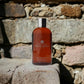 Molton Brown Flame Tree & Pimento Duschgel Flasche vor Steinmauer, Luxus-Kosmetik