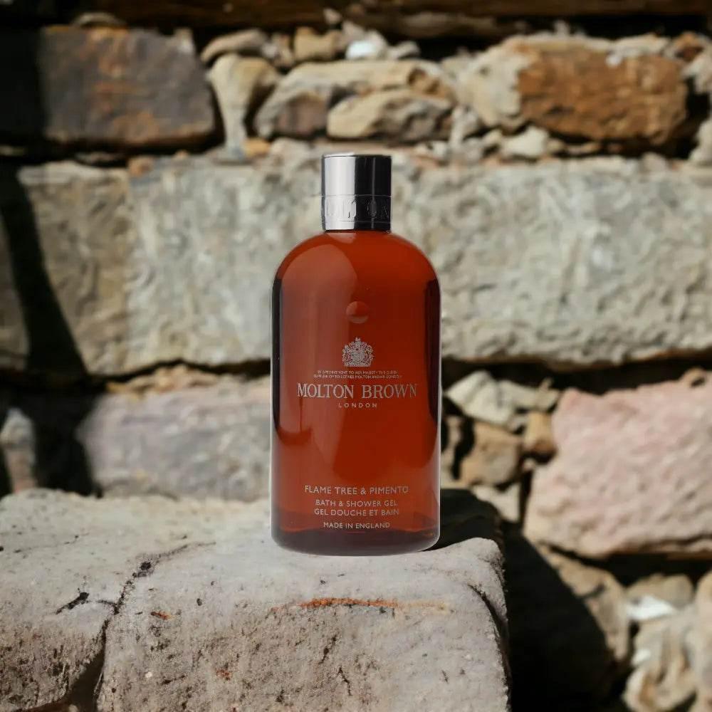Molton Brown Flame Tree & Pimento Duschgel Flasche vor Steinmauer, Luxus-Kosmetik