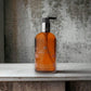 Handseife in bernsteinfarbener Pumpflasche mit floralem Design auf Marmoroberfläche