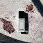 Hydra Beauty Micro Serum Flakon auf marmoriertem Untergrund mit Schatten und Erde