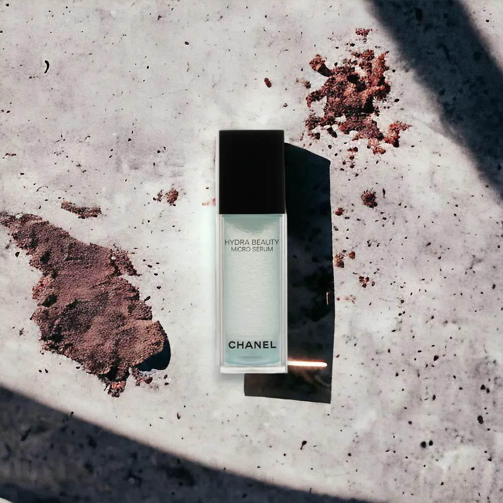 Hydra Beauty Micro Serum Flakon auf marmoriertem Untergrund mit Schatten und Erde