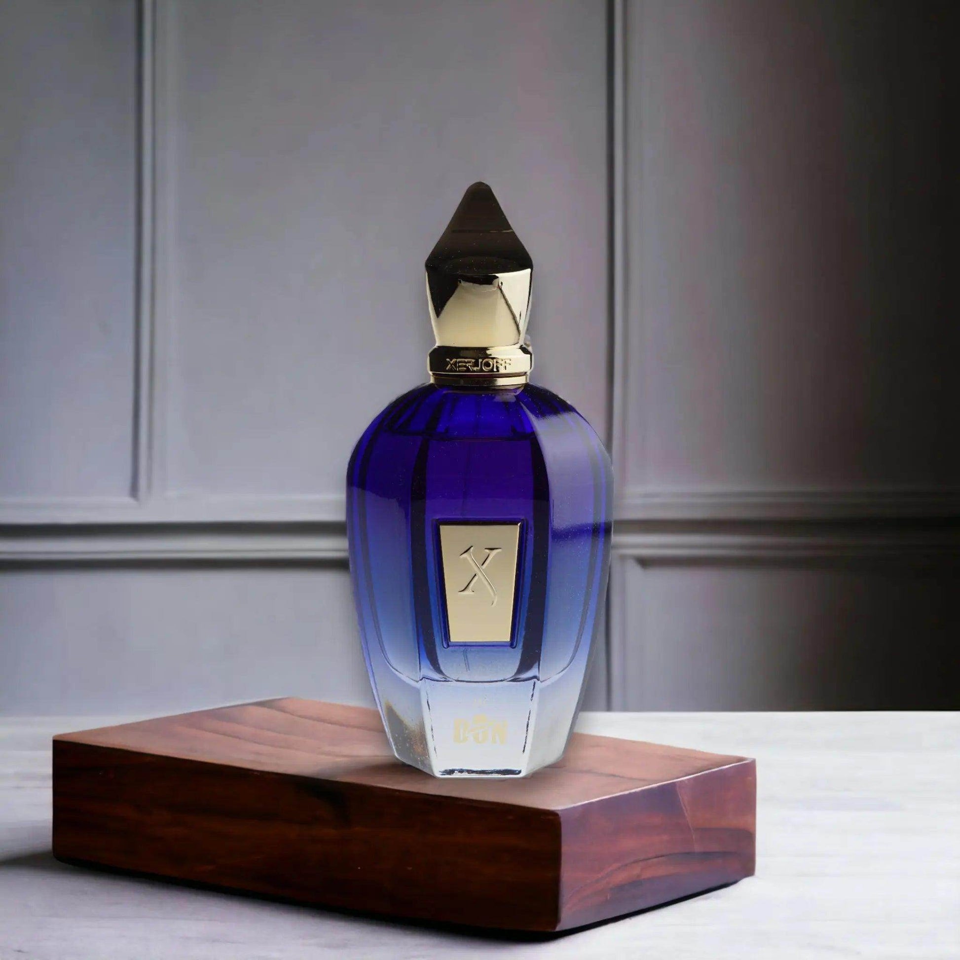 Luxuriöser blauer Parfumflakon mit goldener Kappe auf Holzsockel, Eau de Parfum.