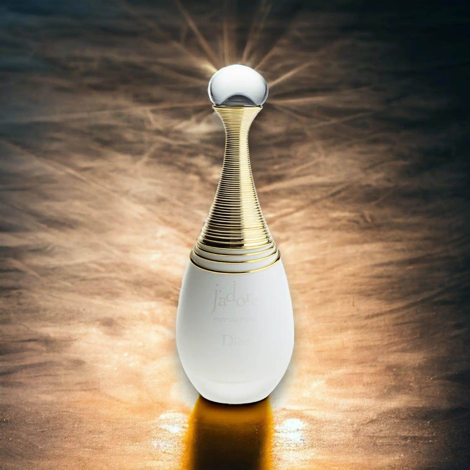 Luxuriöses J'adore Parfum d'eau in eleganter weiß-goldener Flasche auf goldenem Hintergrund.