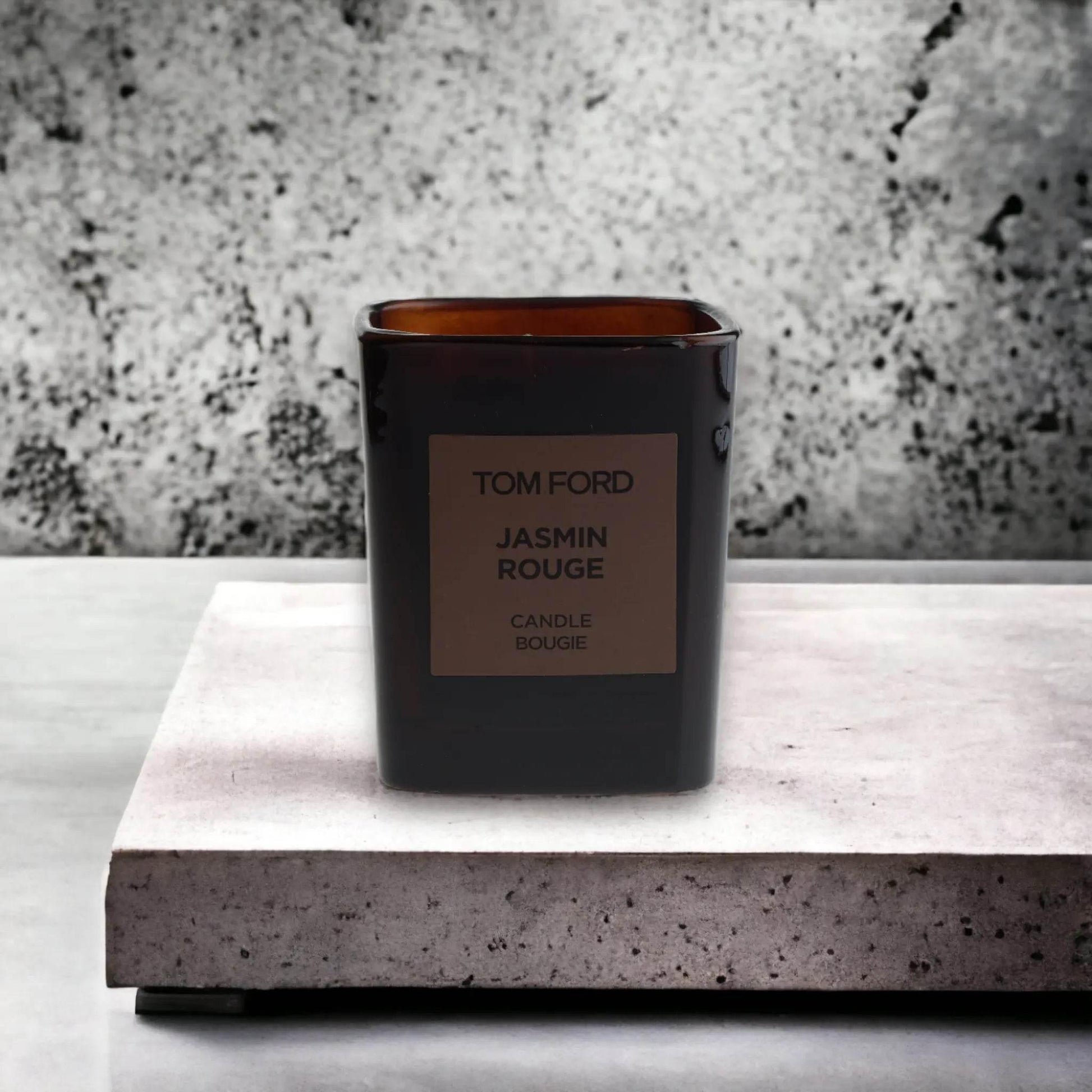 Luxuriöse Duftkerze Jasmin Rouge in dunklem Glasbehälter auf Betonuntergrund
