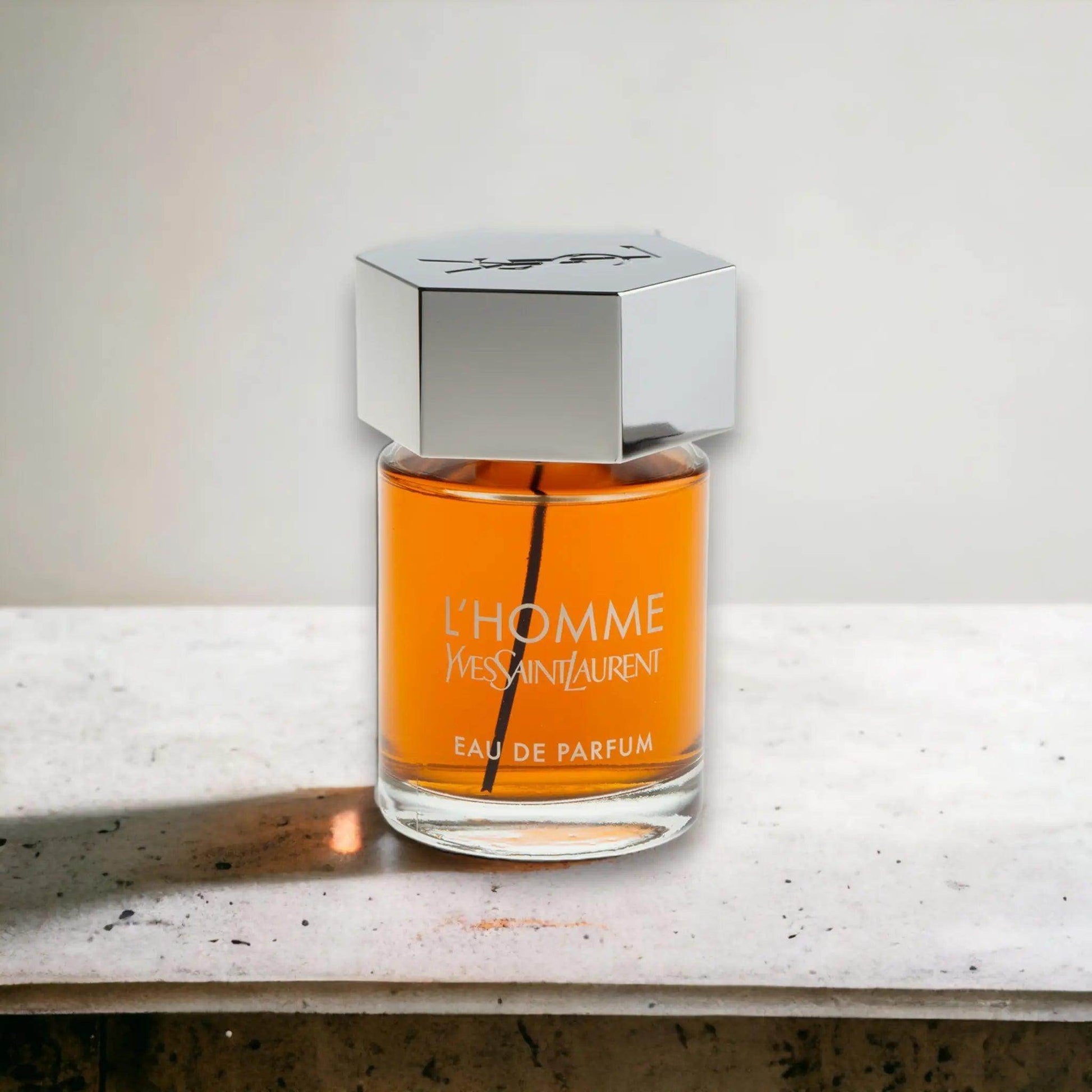 L'Homme Eau de Parfum Flakon mit silbernem Deckel auf hellem Stein, luxuriöses Herrenparfum