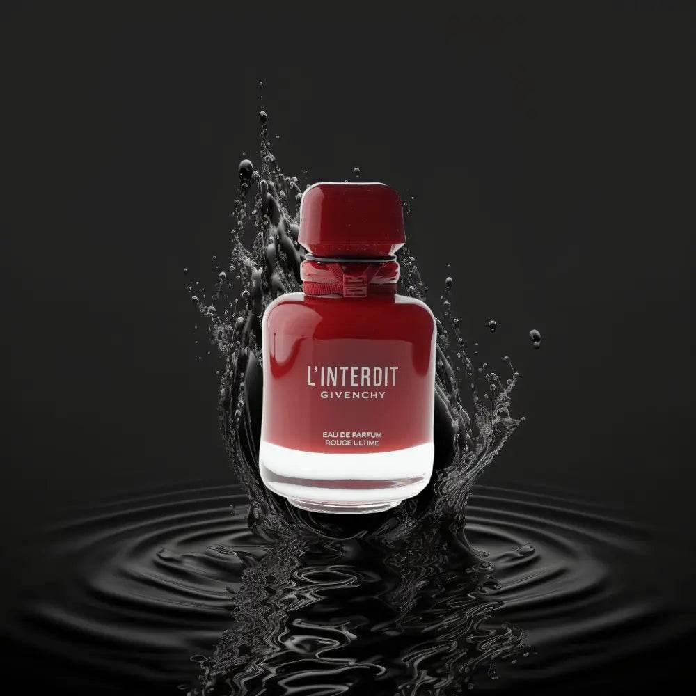 Rotes Parfumflakon L'Interdit Eau de Parfum mit Wasserspritzern auf schwarzem Hintergrund