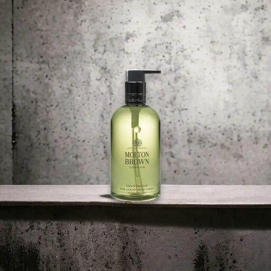 Molton Brown Handseife Lime & Patchouli in grüner Pumpflasche vor Betonwand