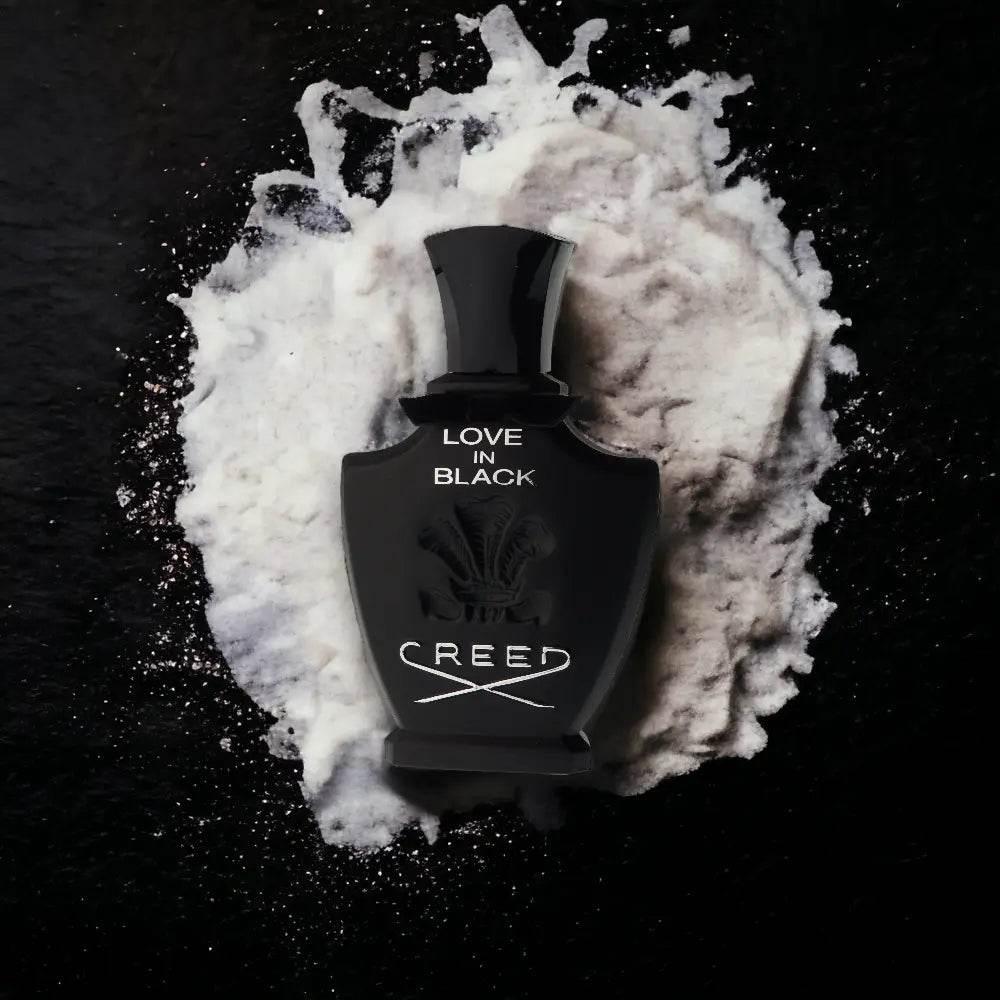 Luxuriöses Parfüm Love in Black in schwarzem Flakon auf weißem Puder auf schwarzem Hintergrund.