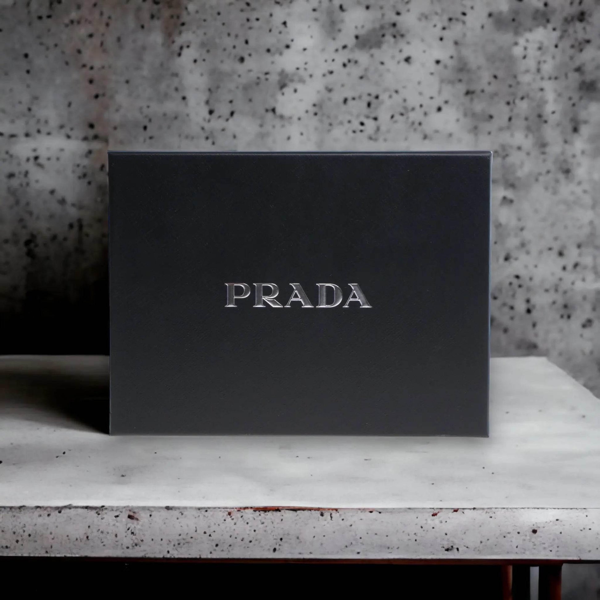 Schwarze Luxus Parfum Geschenkbox mit silbernem PRADA Schriftzug, elegant auf Tisch