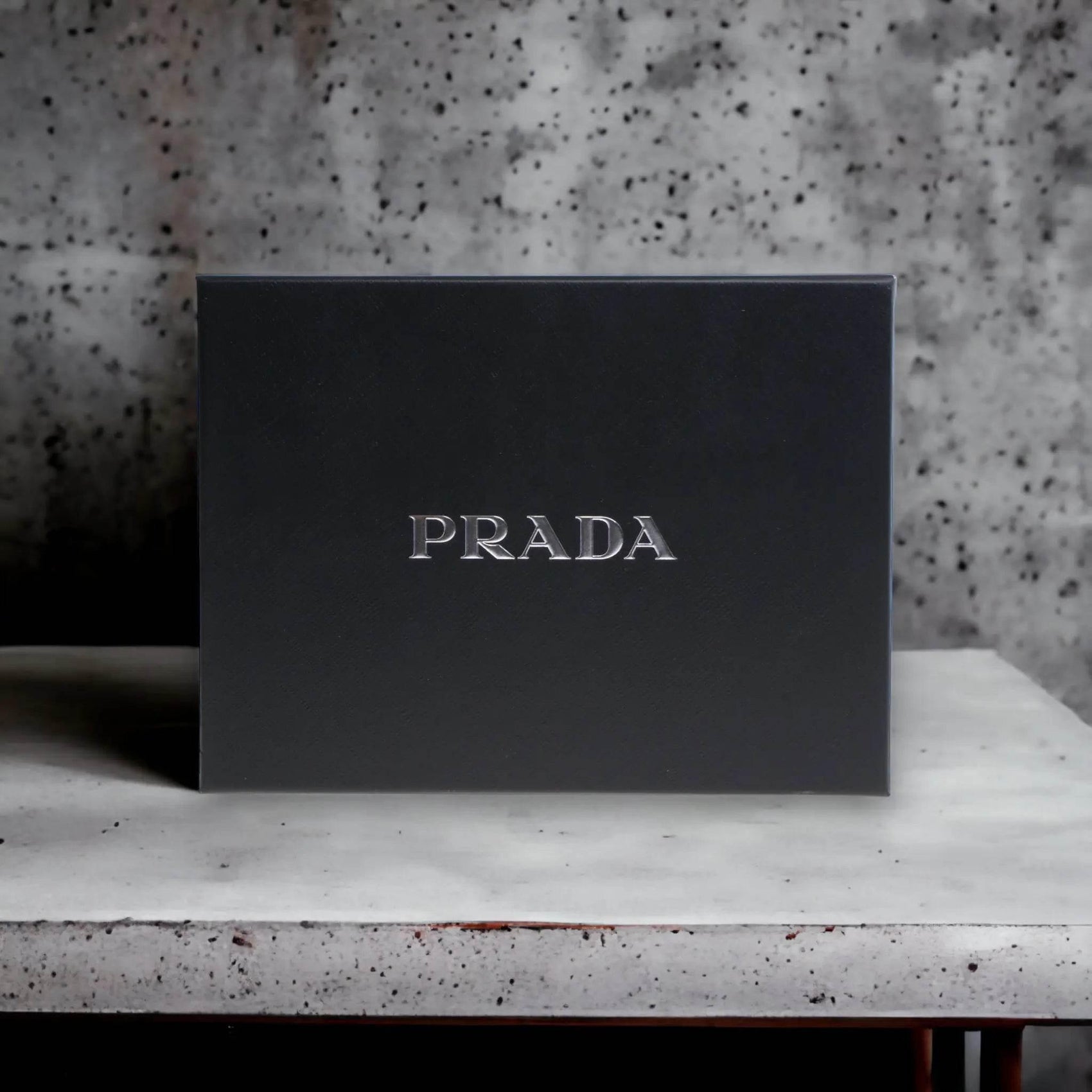 Schwarze PRADA Geschenkbox auf hellem Steintisch, elegantes Parfum-Set Verpackungsdesign.