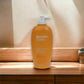 Biotherm Oil Therapy Körperbalsam Flasche auf Holzoberfläche im Licht