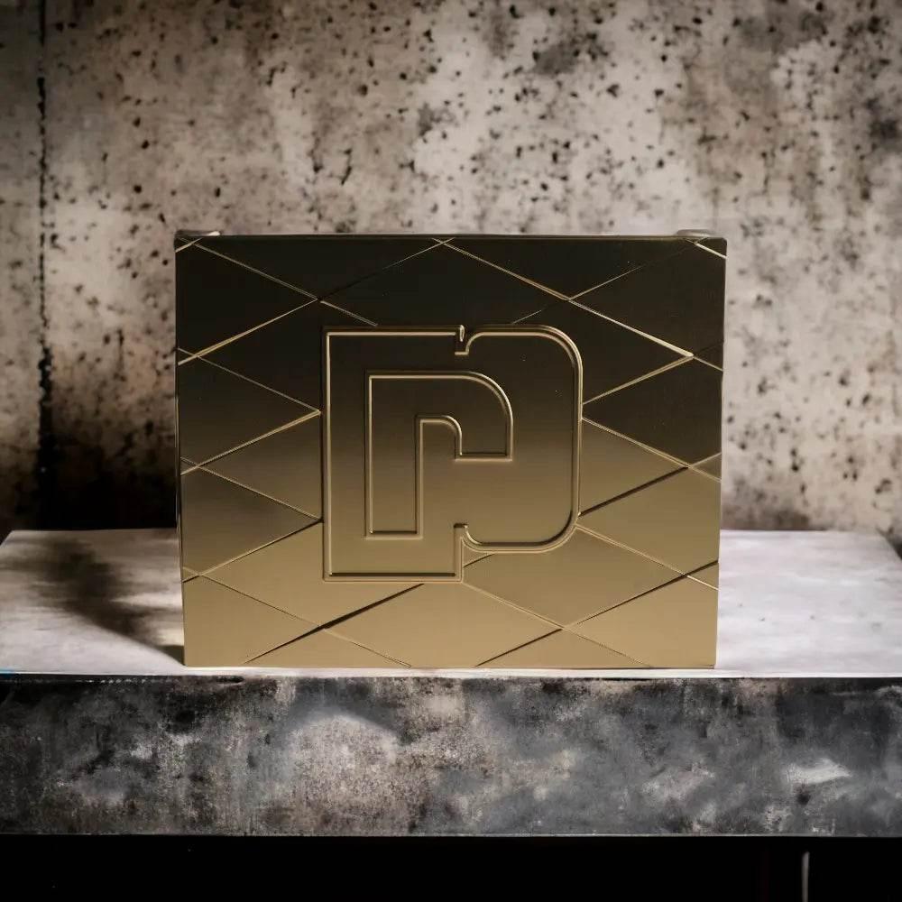 Goldene Parfum Geschenkbox mit geometrischem Muster vor Marmorhintergrund