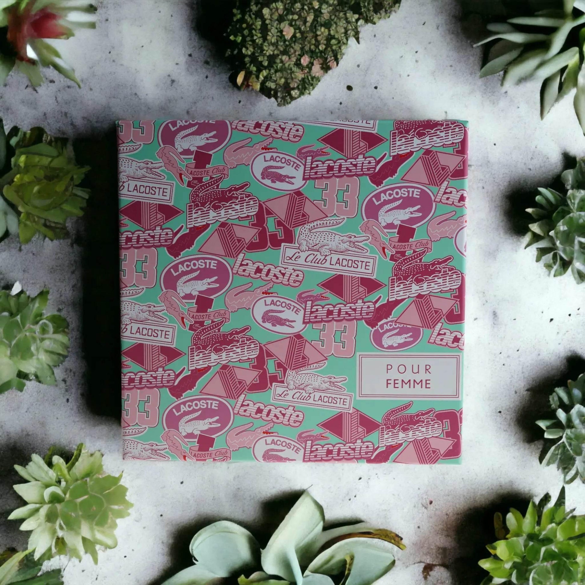 Lacoste Pour Femme Geschenkset mit Musterverpackung, umgeben von Sukkulenten
