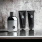 Moncler Pour Homme Duftset mit silberner Parfumflasche, Duschgel und Shampoo auf Marmoroberfläche