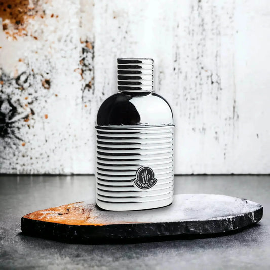 Moncler Pour Homme Parfümflakon, silber glänzend, auf Steinplatte vor heller Wand