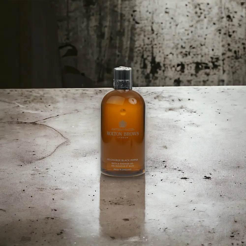 Molton Brown Re-Charge Black Pepper Duschgel Flasche auf Betonoberfläche, luxuriöse Körperpflege