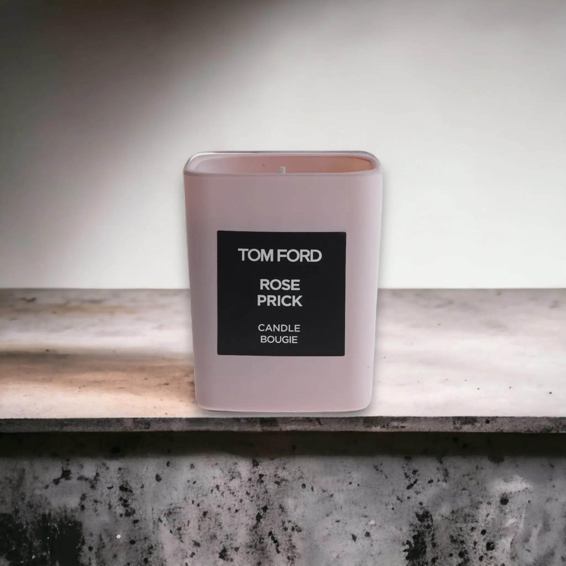 Duftkerze Rose Prick von Tom Ford in eckigem, hellrosafarbenem Glas auf Steintisch