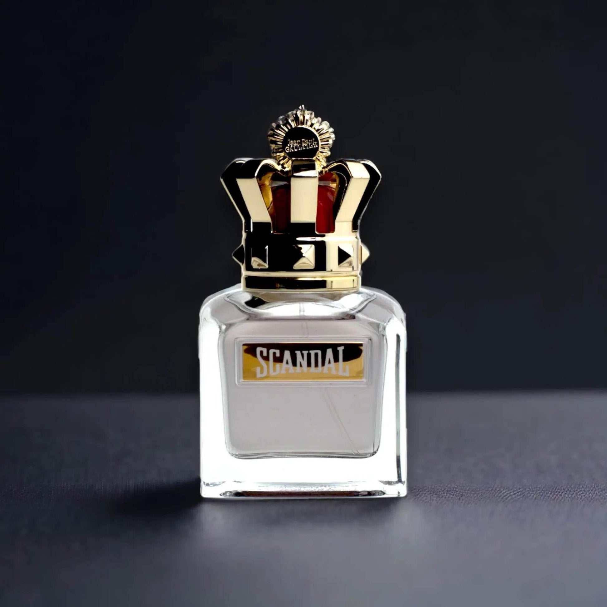 Luxuriöser Parfumflakon mit goldener Krone und Scandal-Schriftzug auf dunklem Hintergrund
