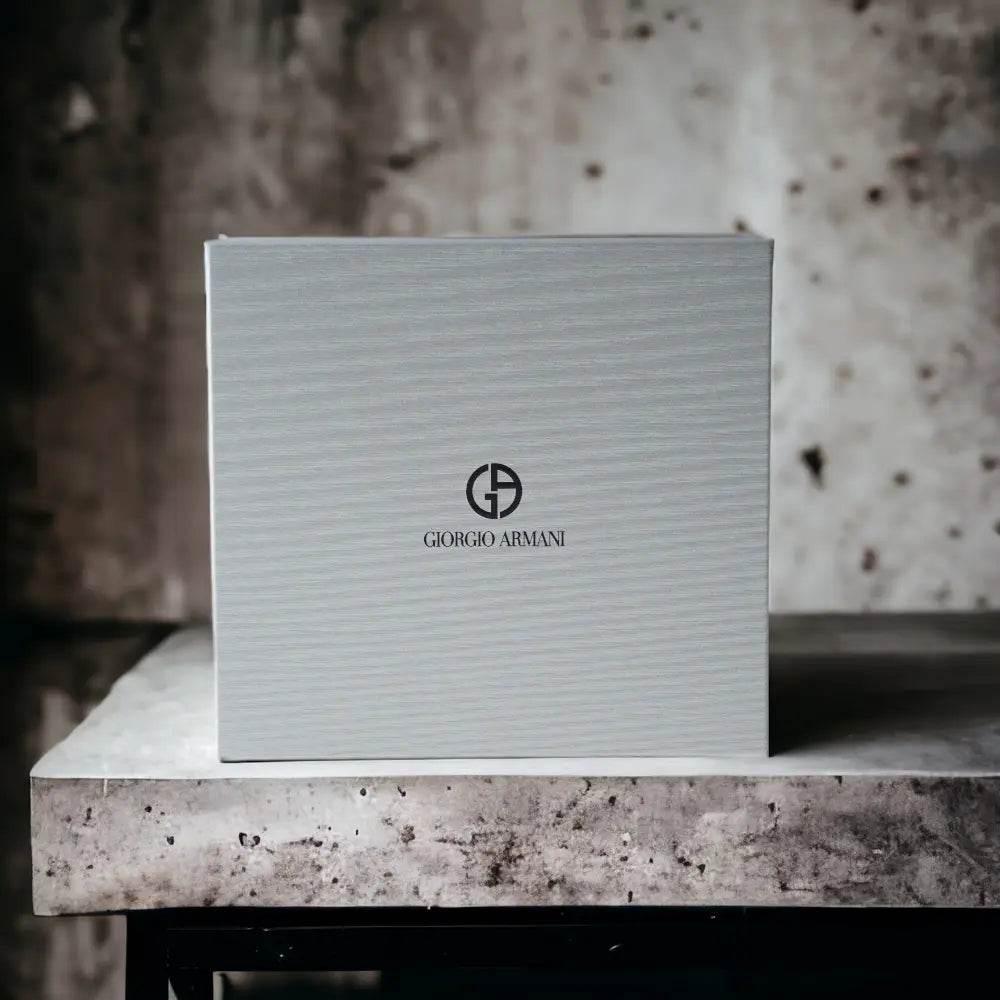 Elegante graue Parfum-Geschenkbox mit Giorgio Armani Logo auf steinernem Untergrund