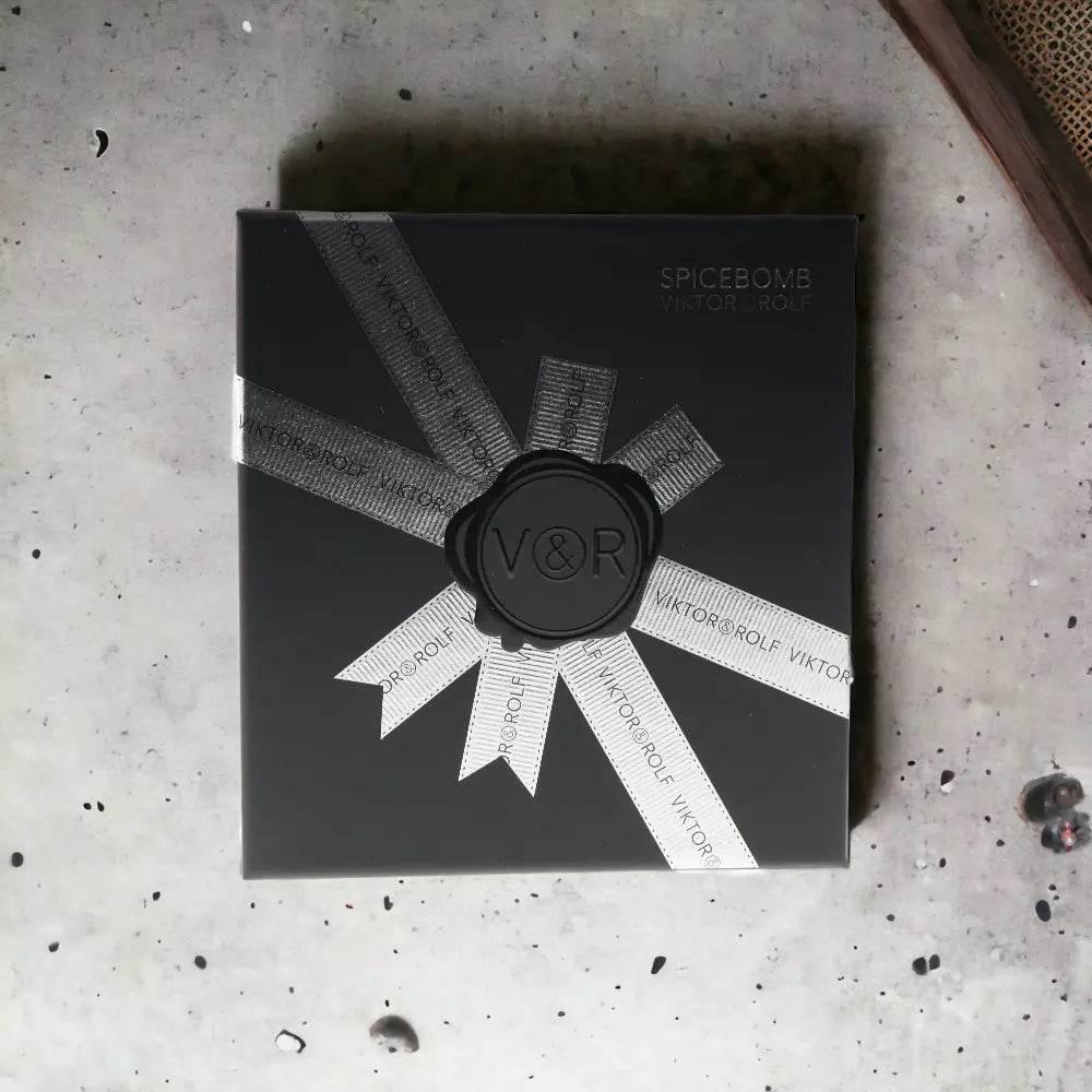 Schwarzes Spicebomb Duftset mit silberner Schleife, elegante Geschenkverpackung auf Steintisch