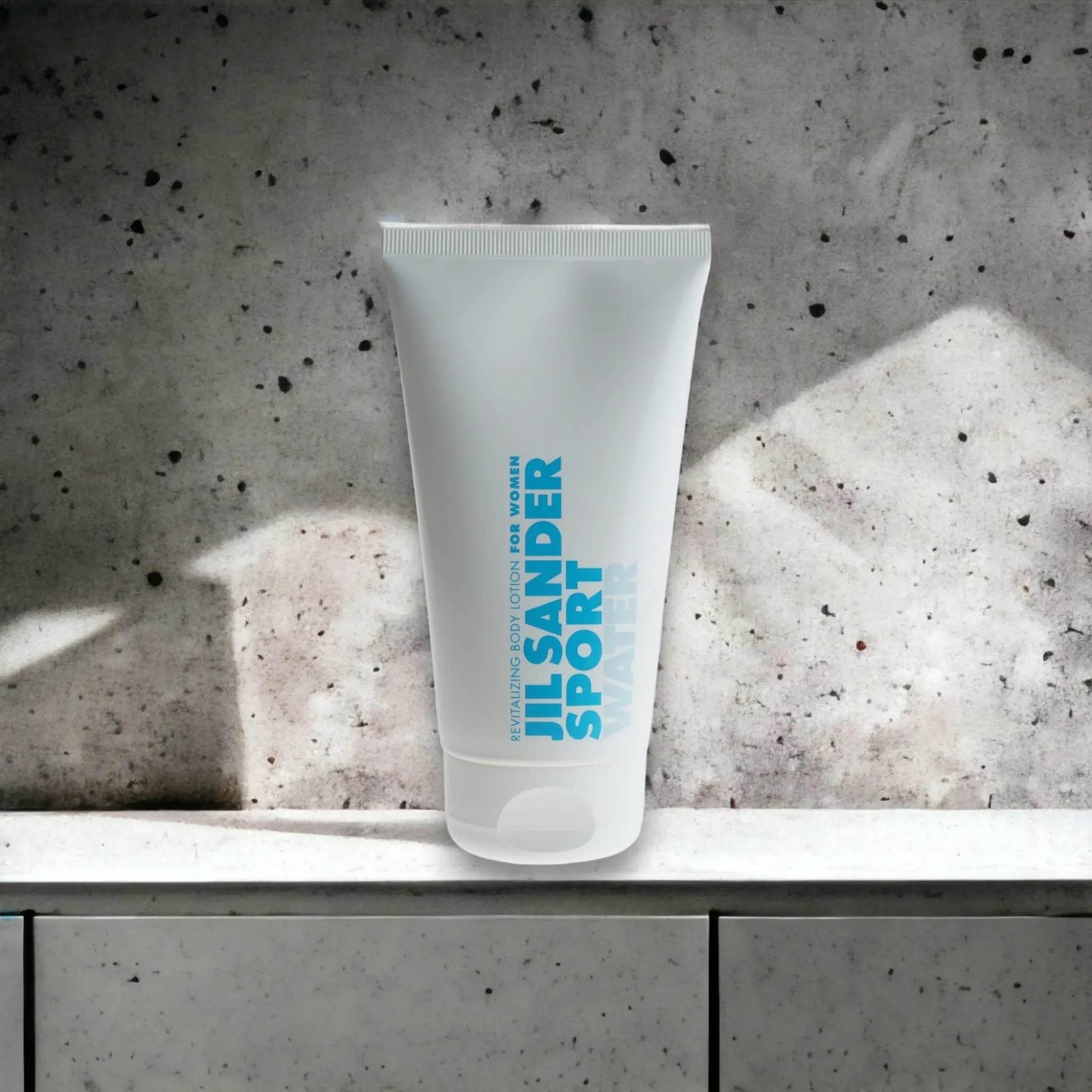 Jil Sander Sport Water Body Lotion für Damen, weiße Tube auf Steinoberfläche